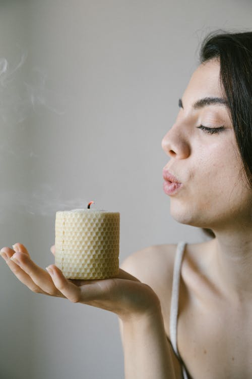 Close-Up Photo of a Woman Blowing an Eco-Friendly Candle