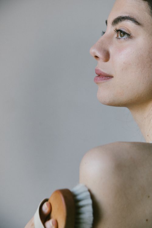 Free A woman embraces eco-friendly self care with an exfoliating body brush, captured in natural light. Stock Photo