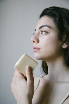 Woman holding organic soap in a natural light setting, promoting eco-friendly beauty.
