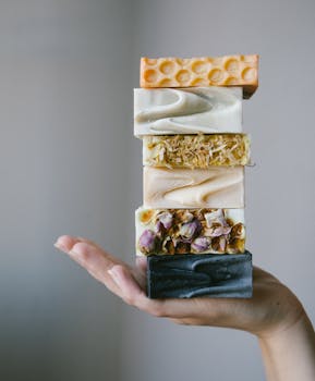 A stack of artisanal organic soaps held by a hand, showcasing natural ingredients.