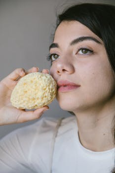 Close-up portrait of woman holding a sea sponge, promoting organic skincare and sustainability.