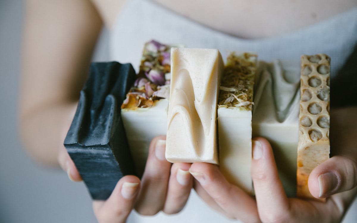 A variety of handcrafted organic soaps held in hands, showcasing natural ingredients and textures.