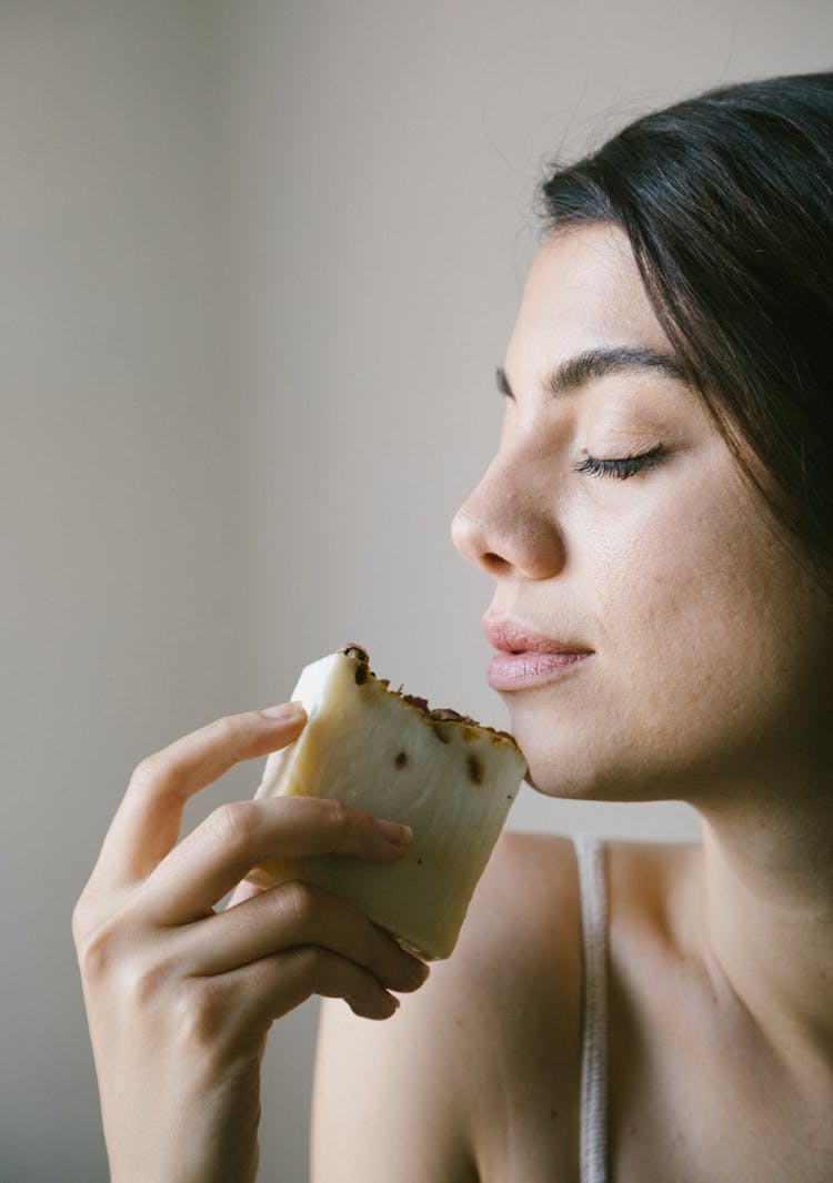 A Woman Holding A Soap Bar Near Her Face