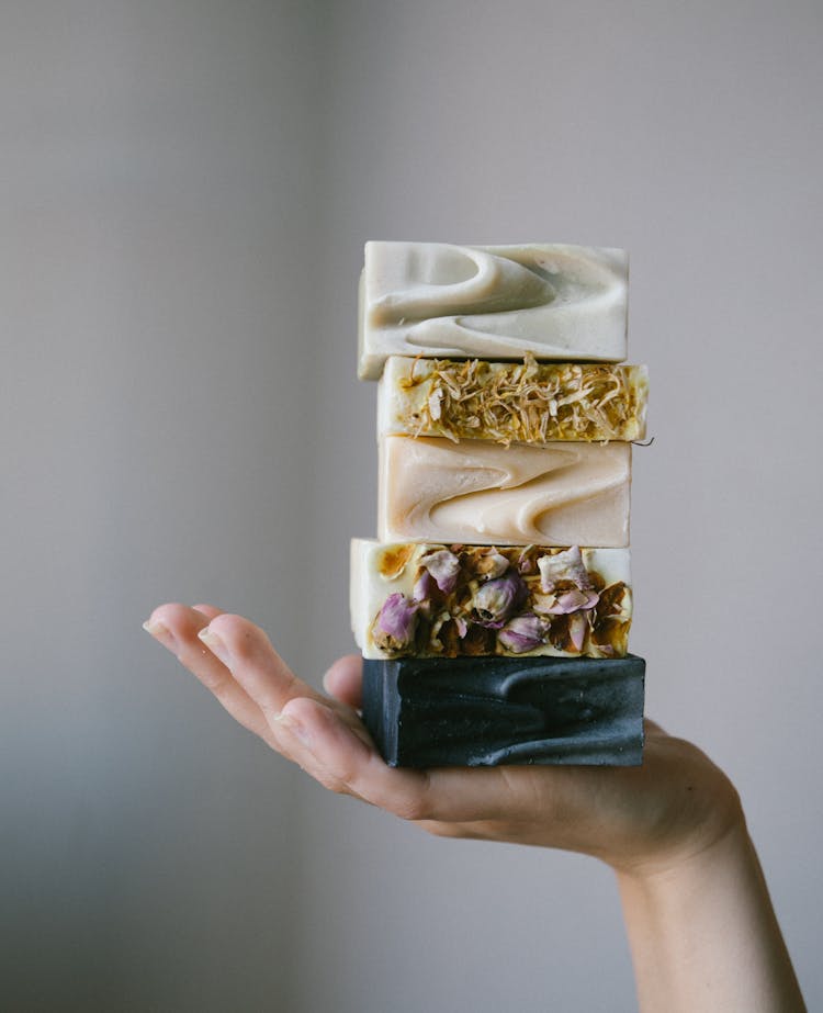 A Person Holding A Pile Of Homemade Soap