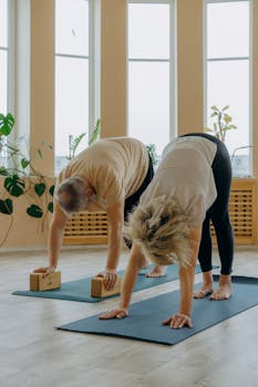 Senior couple engaging in a yoga session indoors with yoga bricks and mats, enhancing flexibility and wellness.