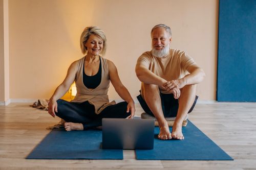 Free An elderly couple practicing yoga at home with online guidance, smiling and relaxed. Stock Photo