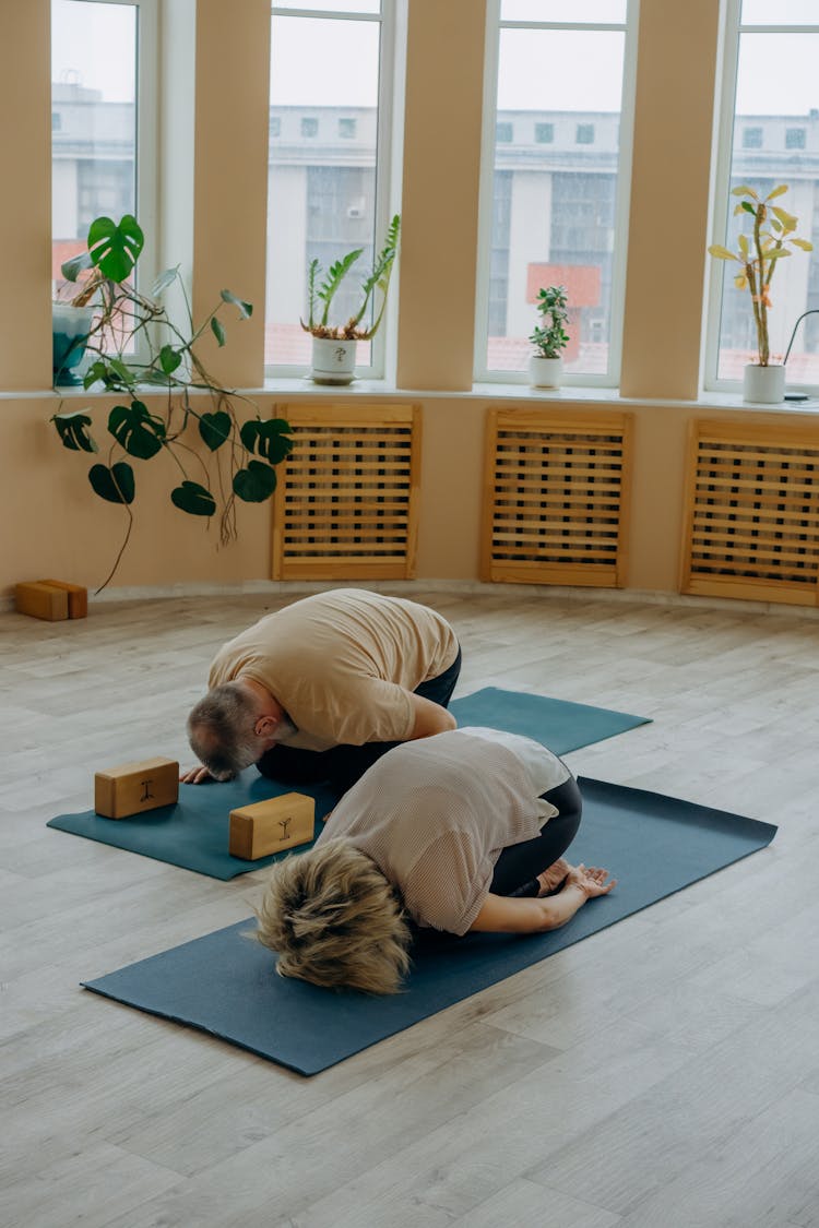 A Man And Woman Meditating On A Yoga Mat