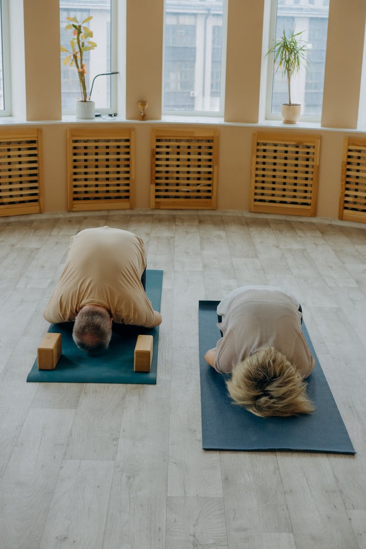 A Man And Woman Meditating On A Yoga Mat