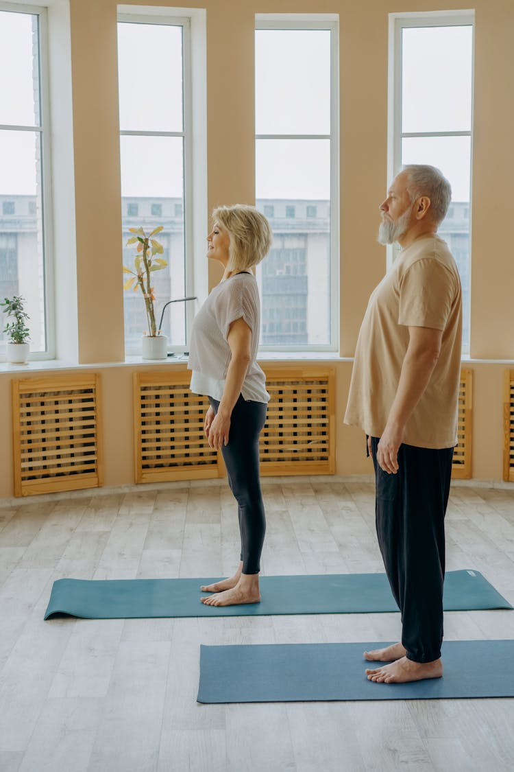 Photo Of An Elderly Man Standing On A Yoga Mat Near A Woman