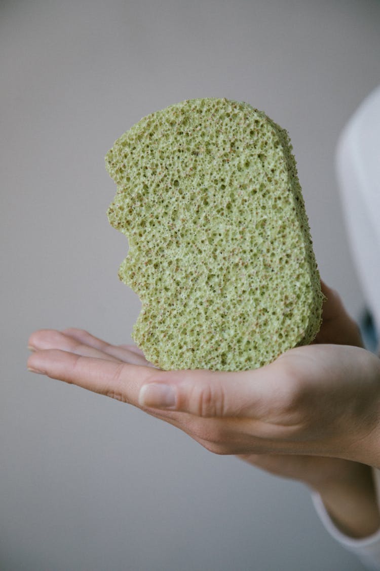 A Green Sponge On A Person's Hand