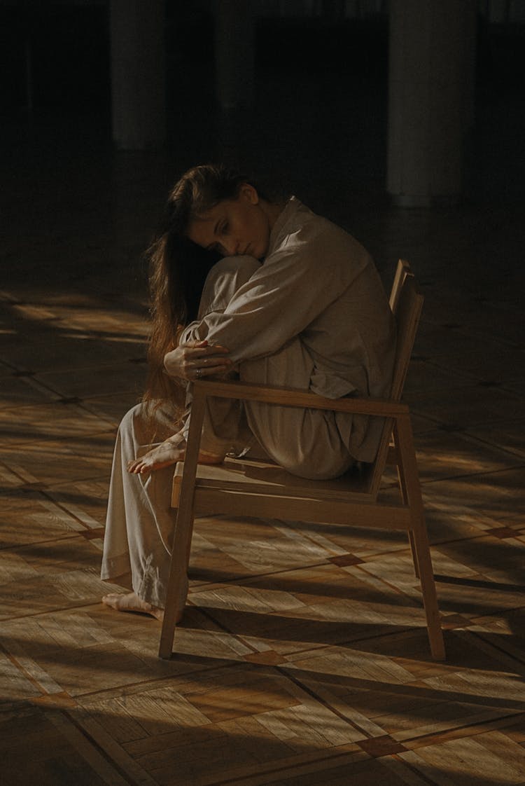 Photo Of A Woman Sitting On A Brown Wooden Chair