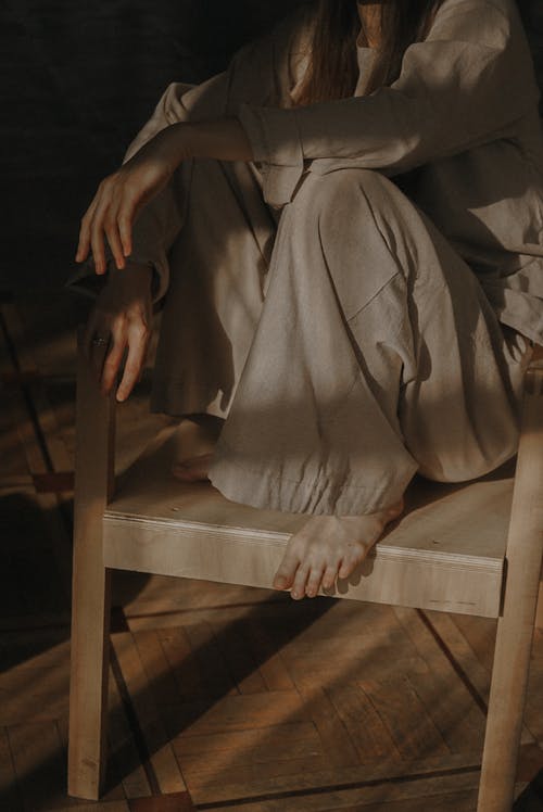 Person in Brown Shirt and Pants Sitting on Wooden Chair