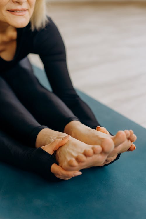 A Person in Activewear Holding their Bare Feet