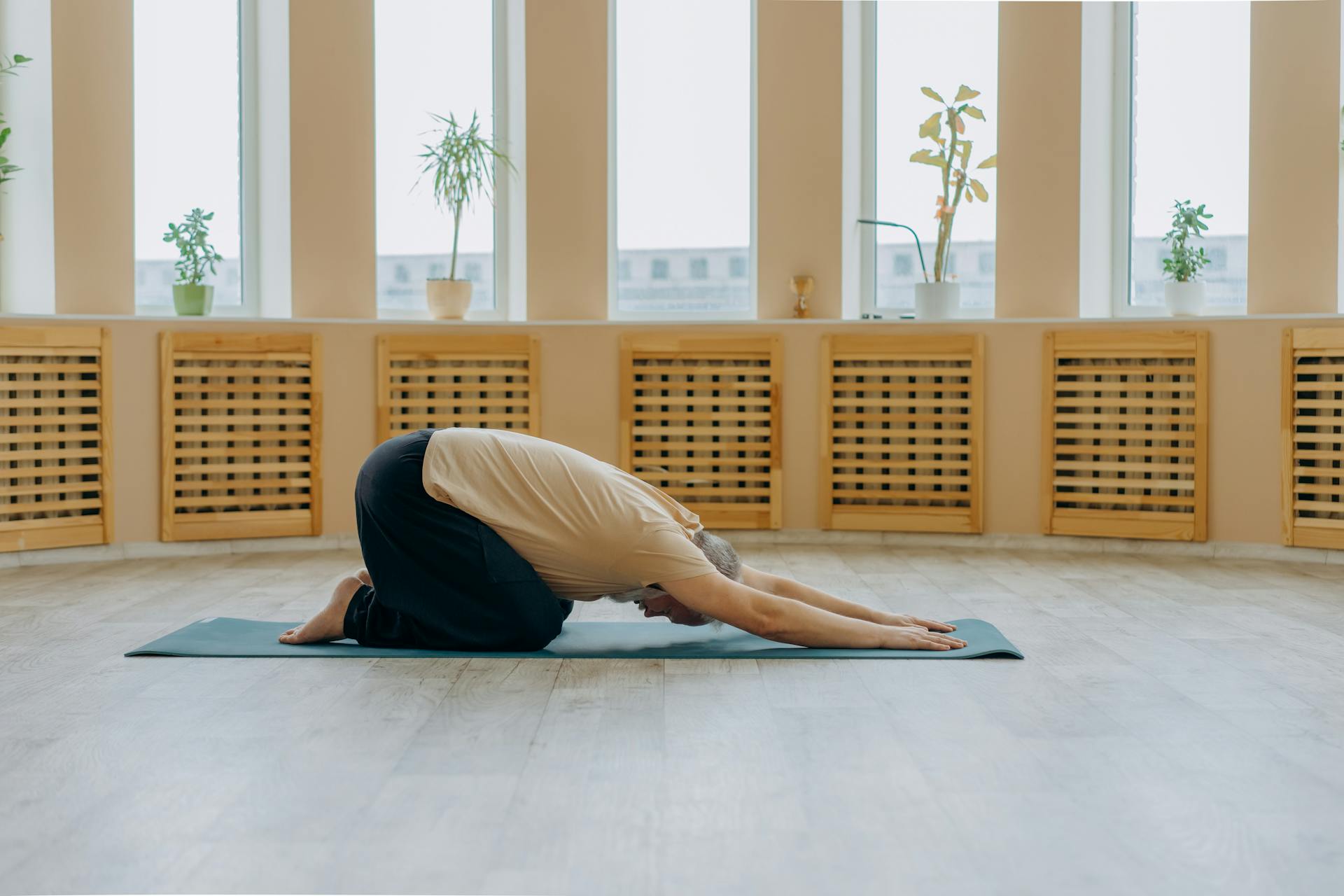 A senior woman stretches in a yoga pose, promoting health and wellness.