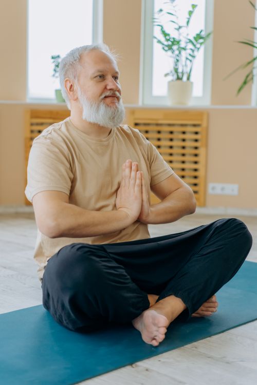 Free Elderly man meditating in yoga pose indoors, promoting fitness and mindfulness. Stock Photo
