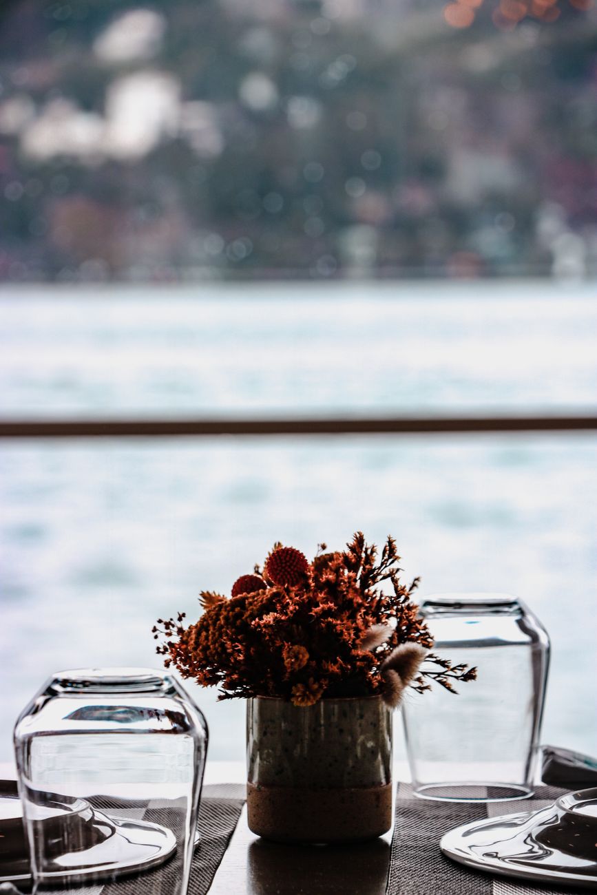A beautiful lakeside table setting featuring a dried floral centerpiece and glass details.