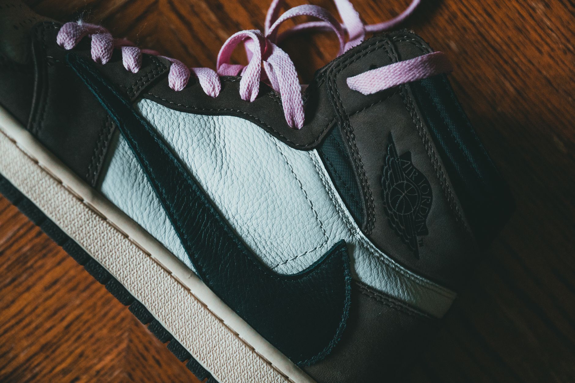 Top view of close up of modern black footwear with pink laces placed on wooden surface