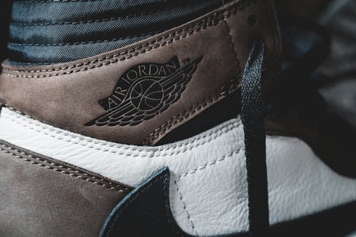Closeup of leather brown untied footwear with black laces and black logo against blurred background