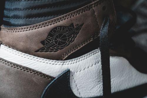 Free Closeup of leather brown untied footwear with black laces and black logo against blurred background Stock Photo