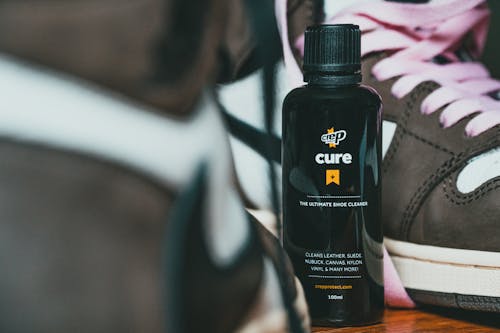Bottle of shoes care product between fashion sneakers