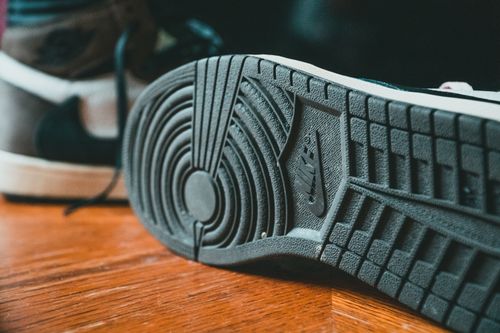 Free Closeup of black rubberized sole of modern stylish sneakers placed on wooden floor Stock Photo