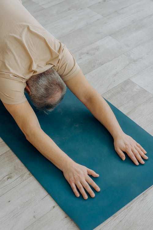 Free Man in Beige Shirt Doing a Forward Bend Stock Photo