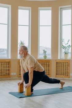 Senior man practicing yoga indoors using blocks for balanced wellness and healthy living.
