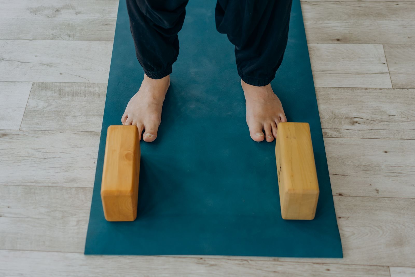 Feet resting on a yoga mat beside wooden yoga blocks, representing a daily yoga practice setup