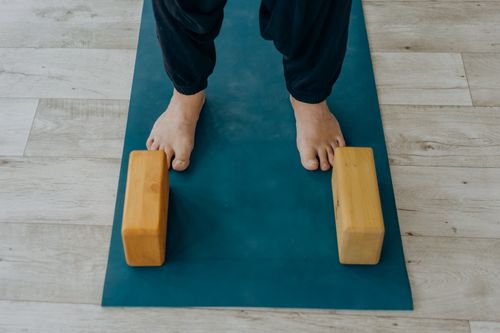 Free Close-up of feet on a yoga mat beside wooden blocks indoors. Stock Photo