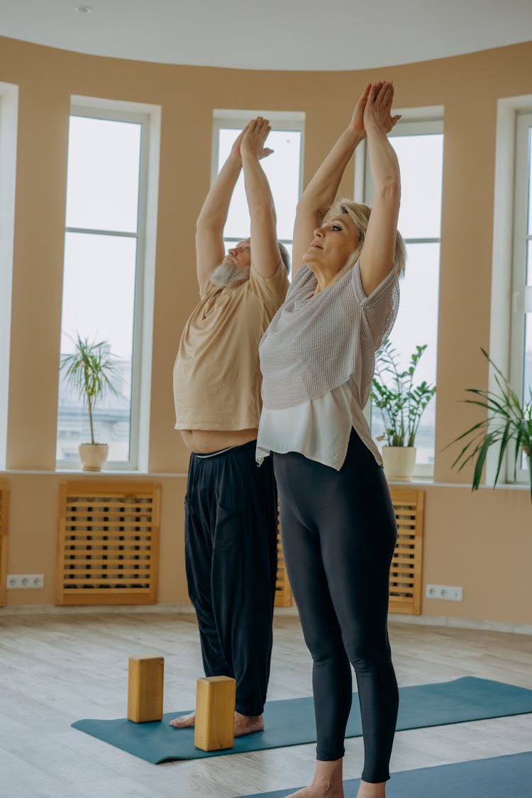 An Elderly Man And Woman Doing A Yoga