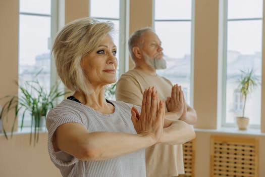 Elderly man and woman engaged in yoga indoors, promoting healthy lifestyle.