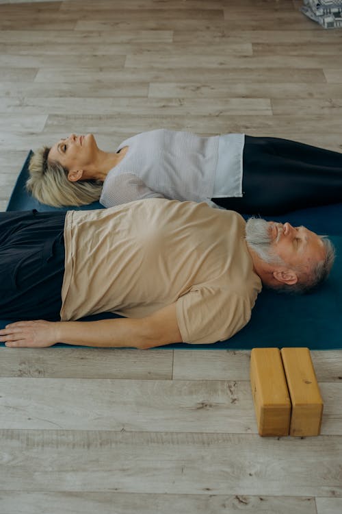 A Man and Woman Lying Down on Yoga Mats 