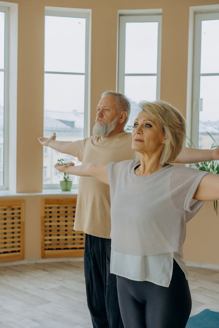 A Man And A Woman Standing With Arms Raised On Sides