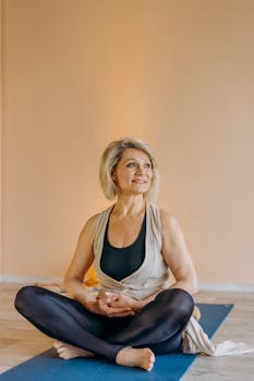 Elderly woman seated in lotus pose on a yoga mat, enjoying relaxation and inner peace.