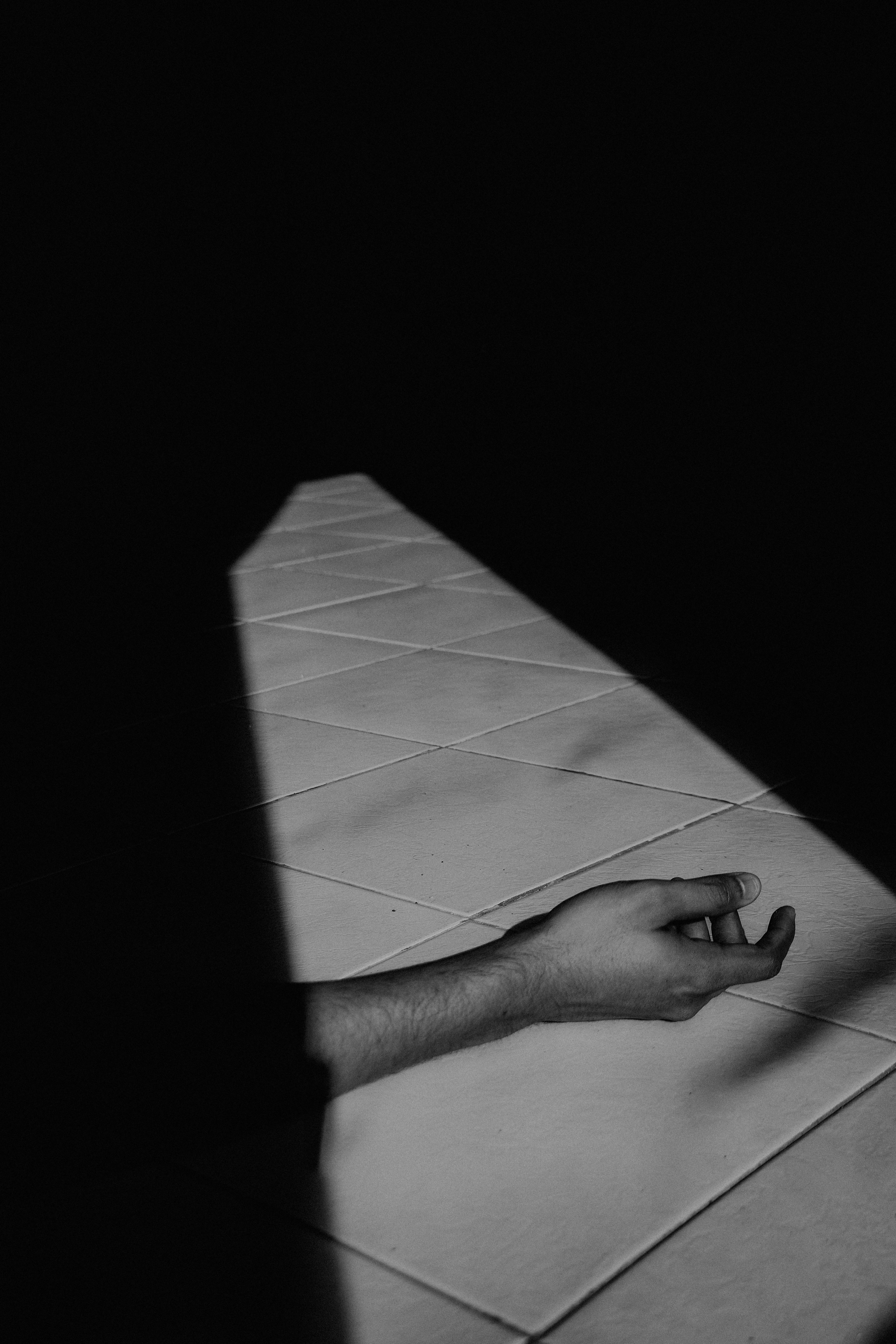 Creative capture of a hand in dramatic shadows on a tiled floor, evoking mystery and artistic flair.