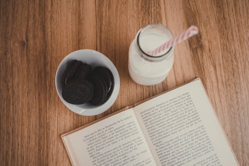 Clear Glass Jar Beside Open Book Page on Brown Wooden Table