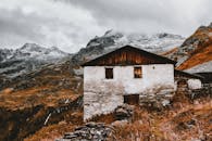 秋天，废弃小屋的风景映衬在白雪皑皑的群山中