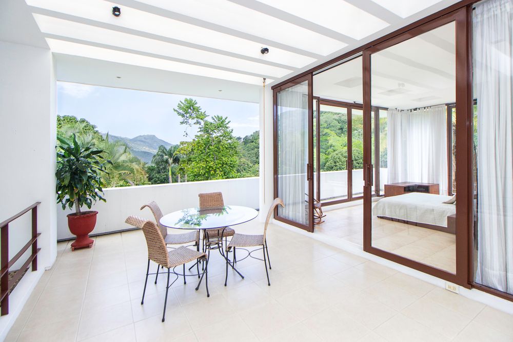 Balcón con sillas y mesa junto a puertas corredizas de cristal