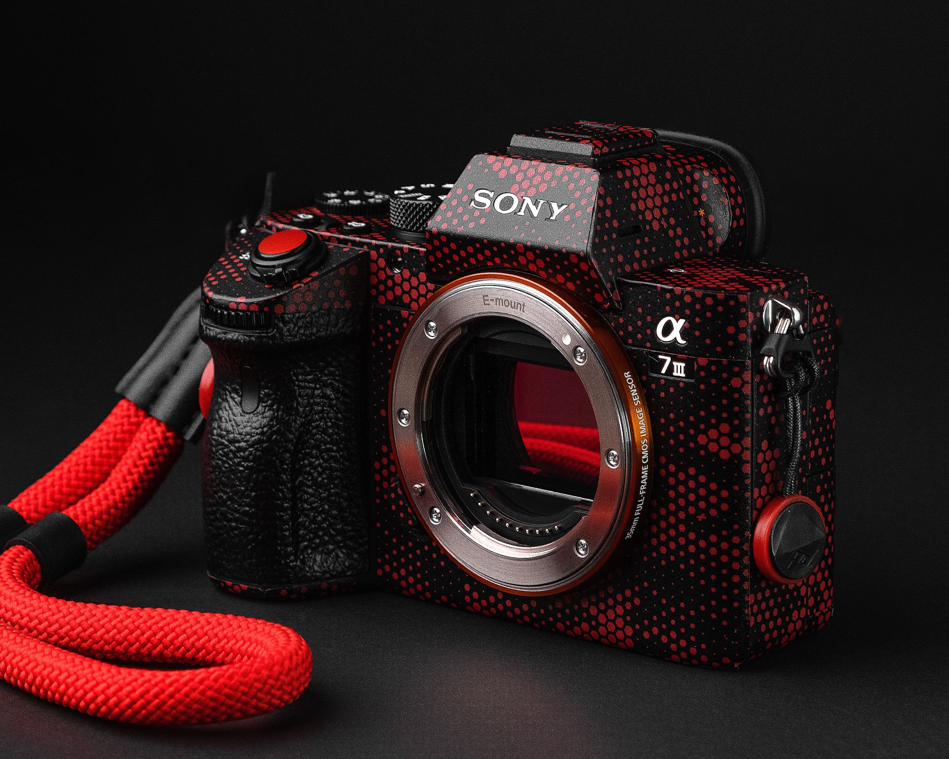 Close-up photo of a Sony camera with a striking red and black skin design against a dark background.