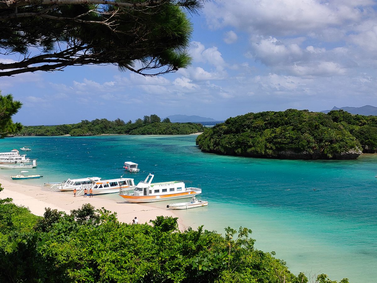 Crystal clear turquoise tropical ocean water with white sandy beach and palm trees in Okinawa Japan
