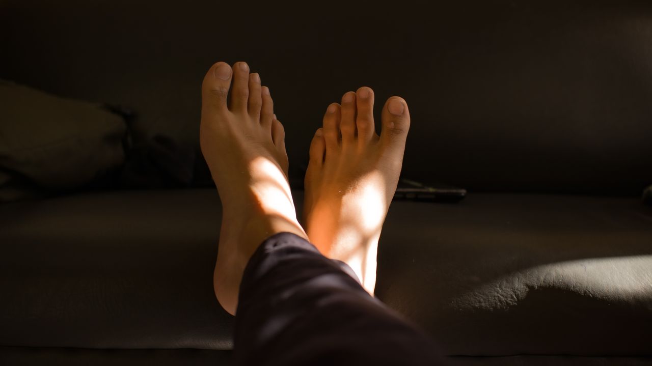 a close up view of relaxed barefoot on a couch with soft lighting crea