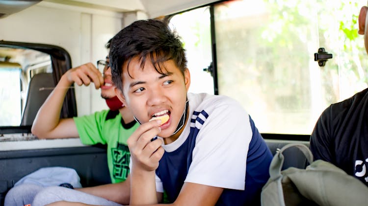 Young Ethnic Boy Eating Cookie In Bus