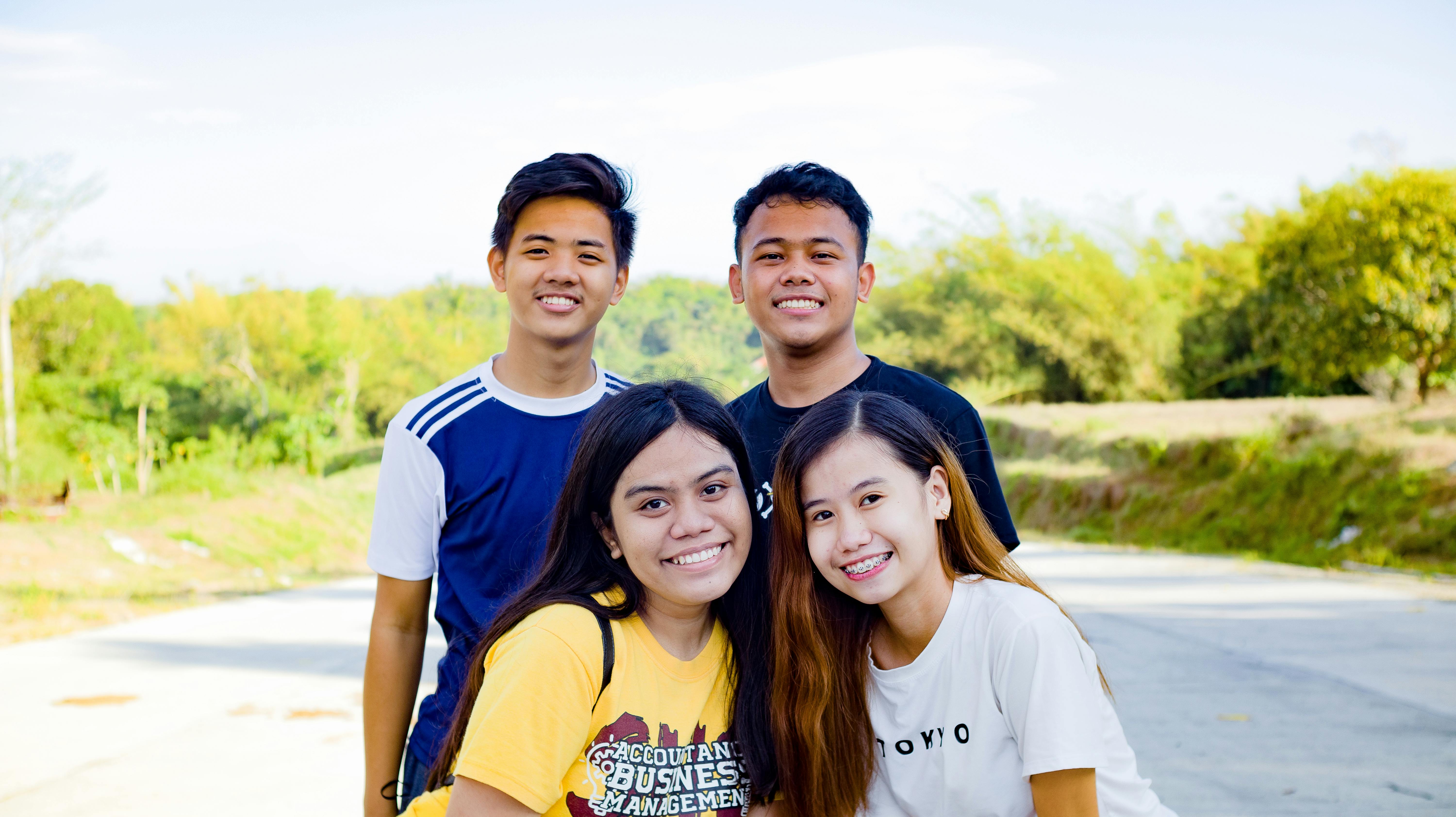 multiracial smiling friends in street near plants