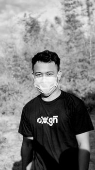 Black and white portrait of unrecognizable young ethnic male in casual t shirt wearing disposable mask in nature - Fotografer Sidoarjo