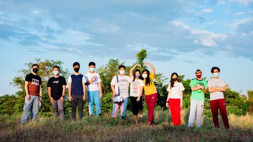 Free Group of multiracial young friends in sportswear and protective masks standing together on grassy lawn in park during summer weekend Stock Photo