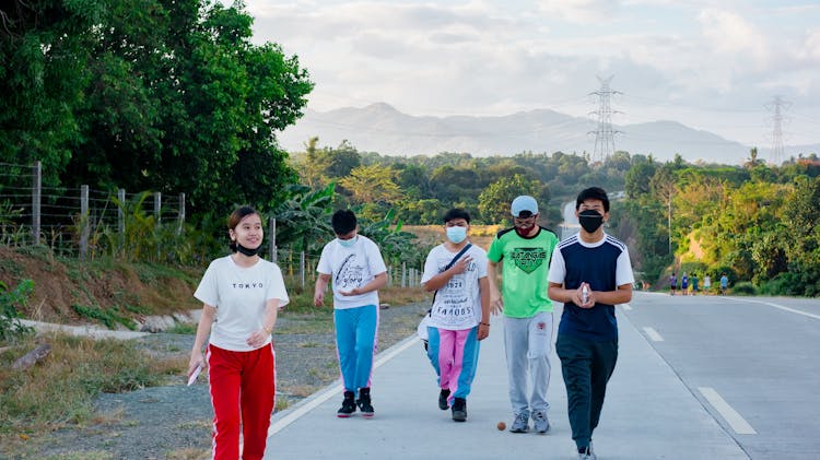 Happy Asian Friends Walking On Road In Countryside