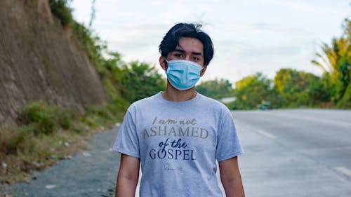 A Man in Gray Shirt Wearing Face Mask Standing on the Roadside