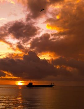 Tranquil sunset over the sea in Danao City, Philippines, with a silhouetted ship and dramatic clouds.