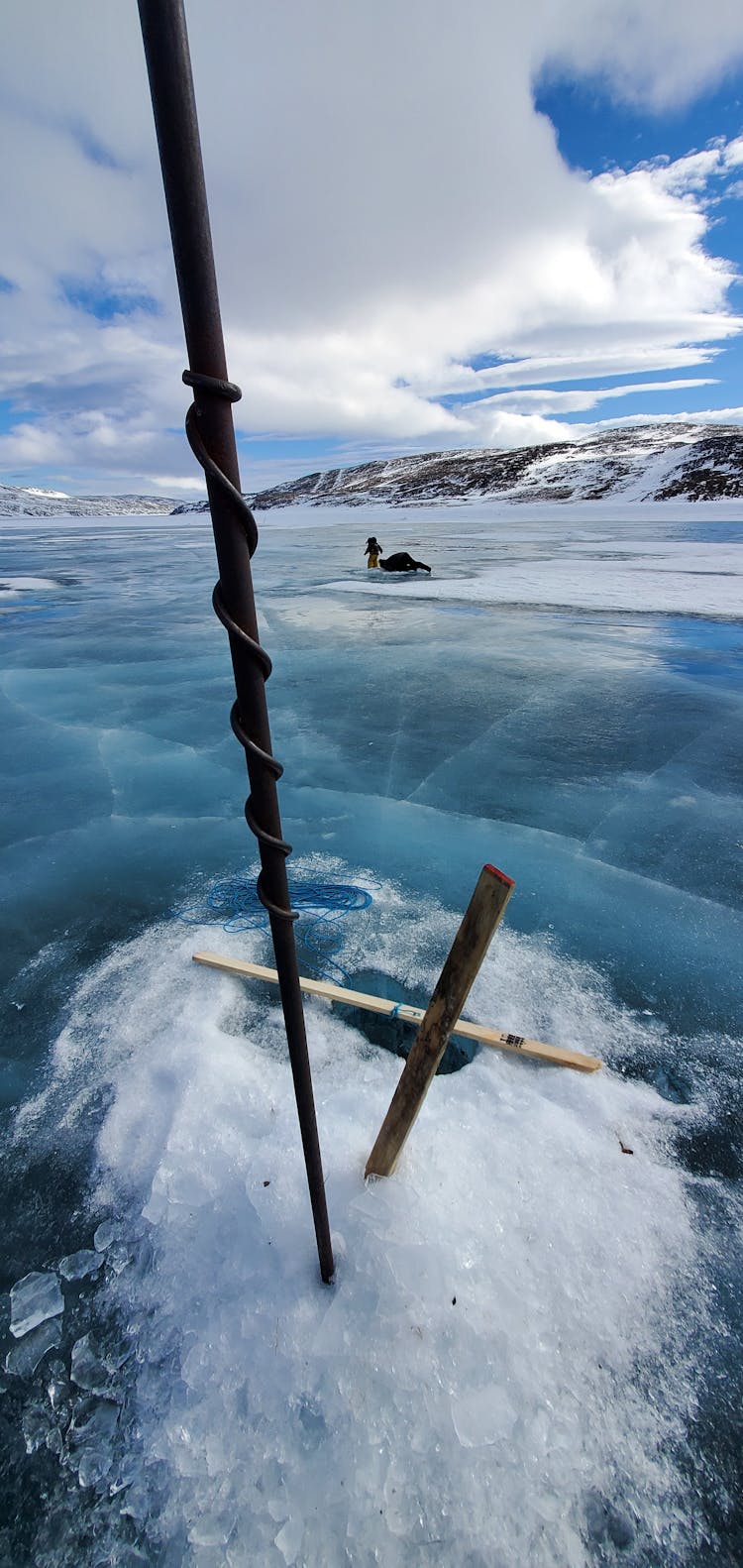 A Person Drilling The Frozen Lake