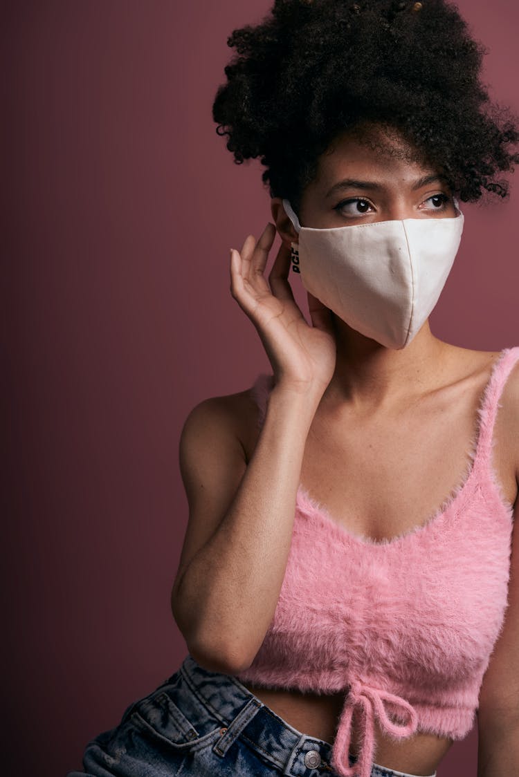 A Woman In Pink Furry Tank Top Wearing A White Face Mask